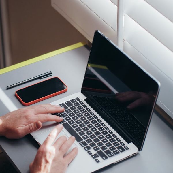 A person stretching near a desk in a home office with morning light.